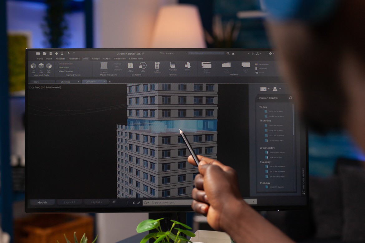 Architect pointing at a 3D building model on a computer screen